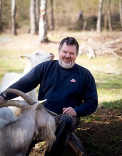 Svein Løken sitter på huk sammen med en geitebukk.
