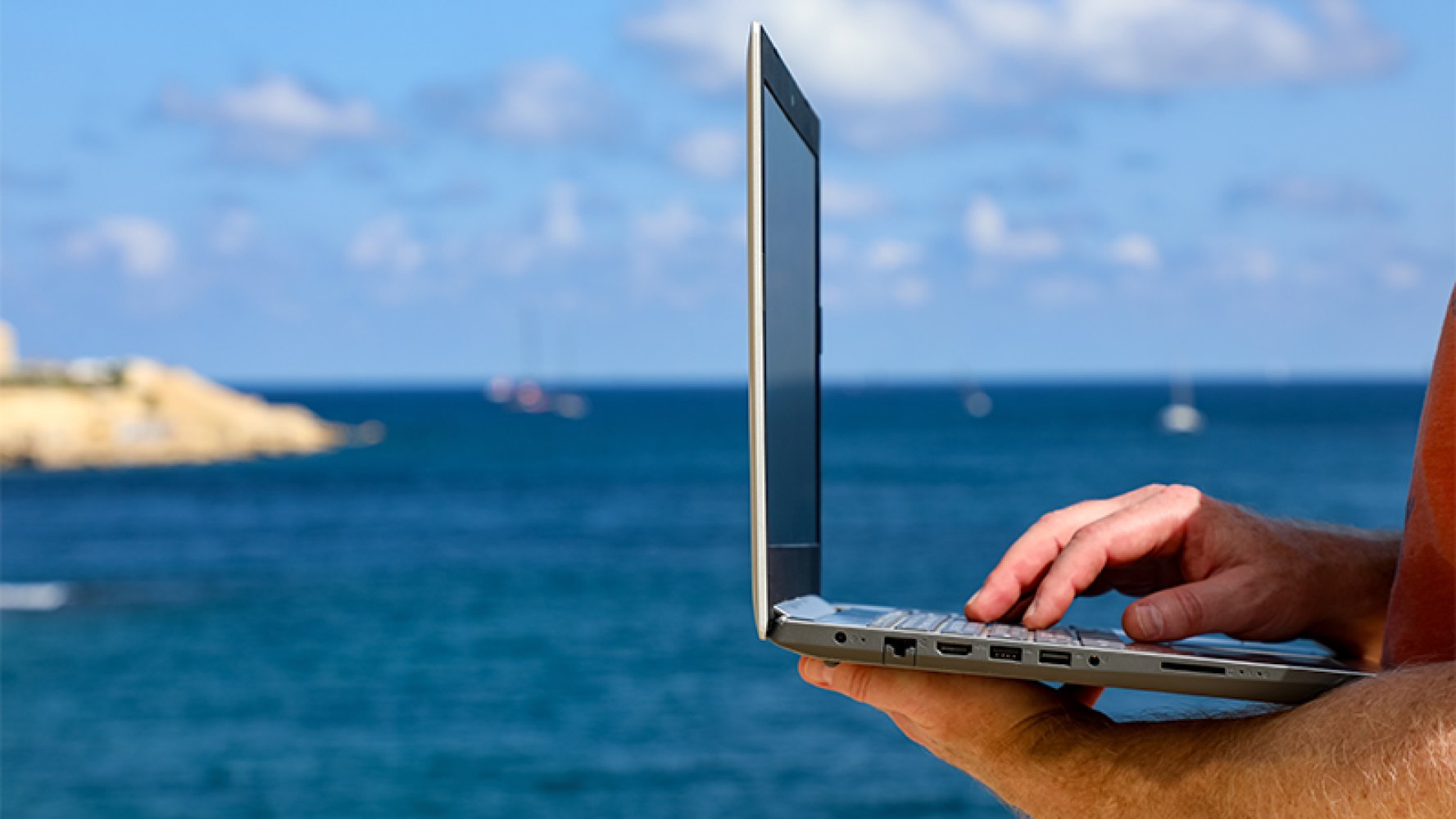 En som holder i en pc på stranda.
