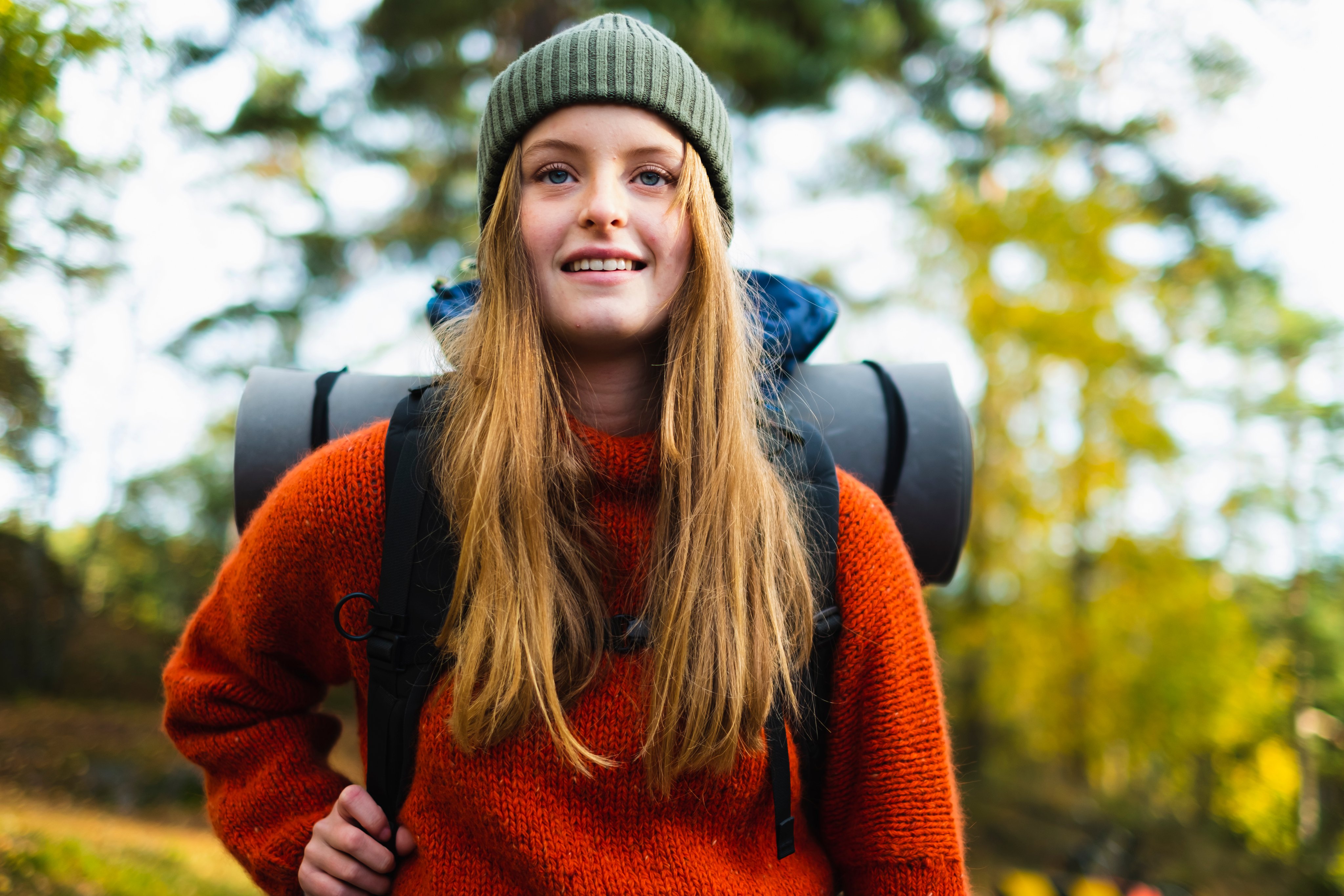 Ung kvinne med ryggsekk ute på tur i skogen.