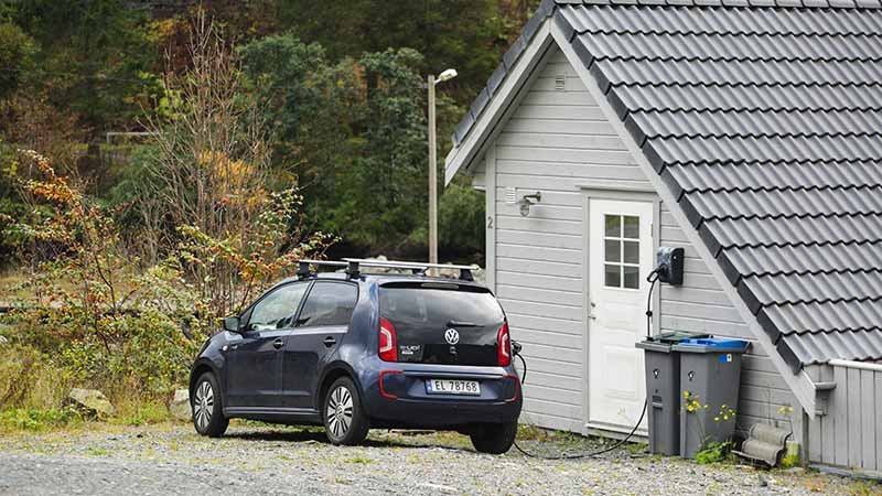 En elbil står og lader utenfor et hus.