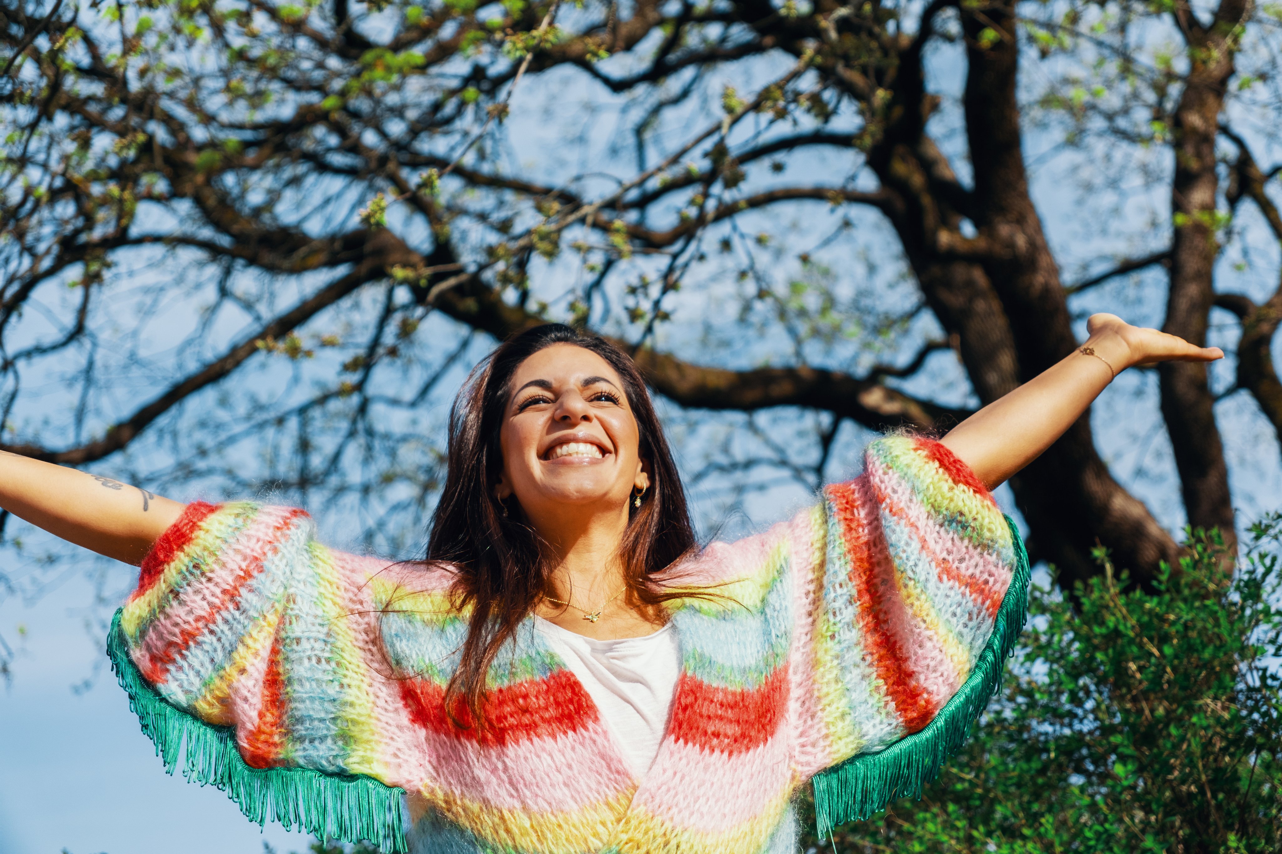 En kvinne smiler og strekker armene ut.