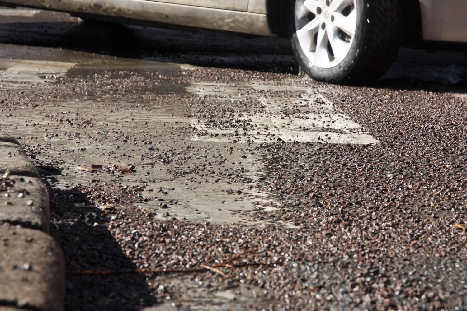 Nærbilde av asfalt med mye grus på bakken.