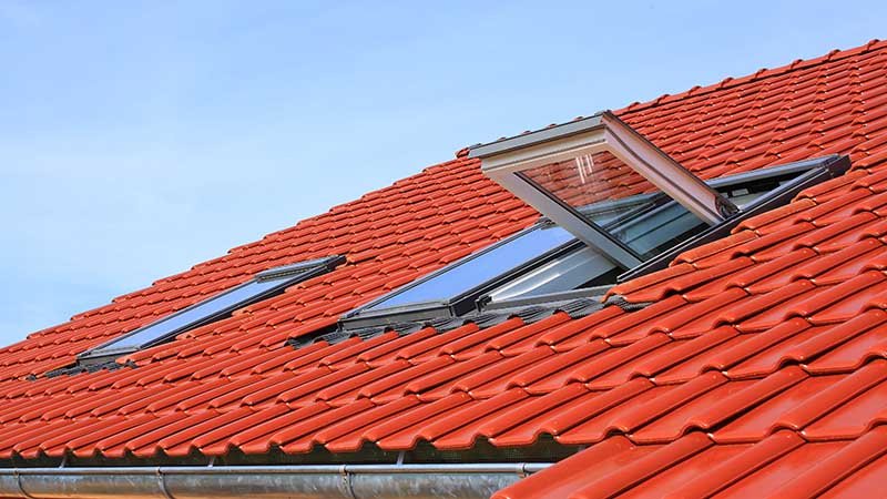Rødt hustak med et takvindu som står åpent