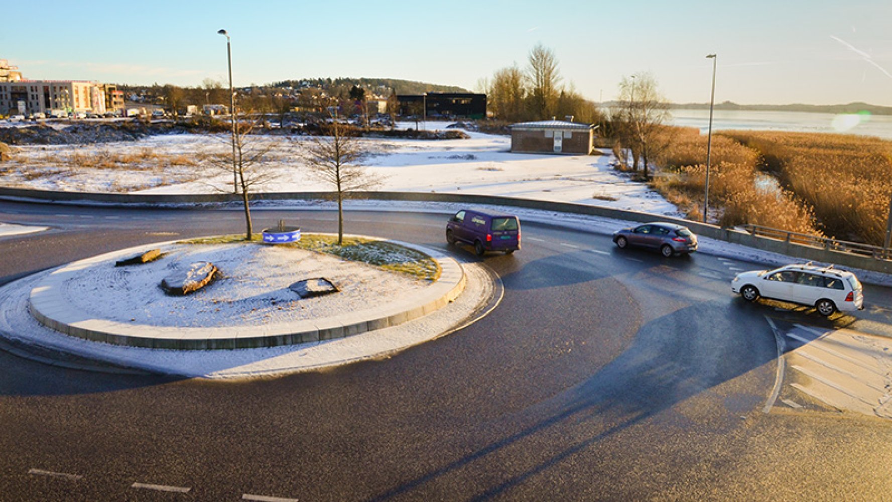 Rundkjøring med flere biler som kjører rundt øyen en kald, solrik vinterdag.