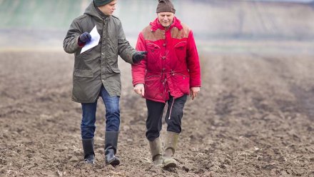 To menn går over pløyet mark.