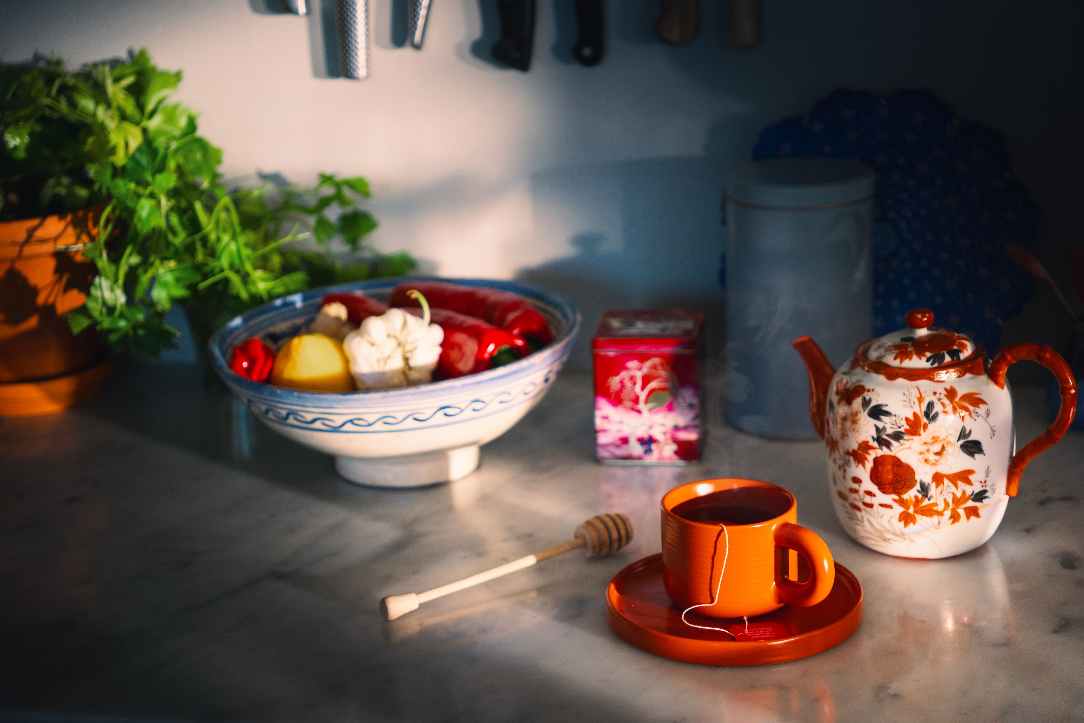 Kjøkkenbenk med tekopp, tekanne og fat med grønnsaker.