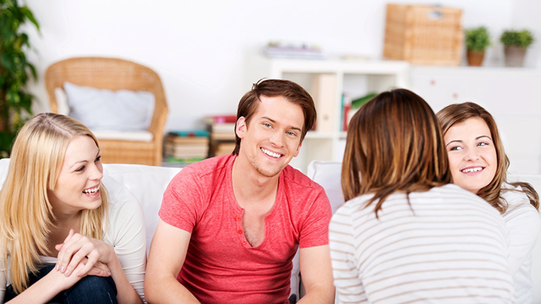 Fire unge personer sitter i en stue og snakker sammen.