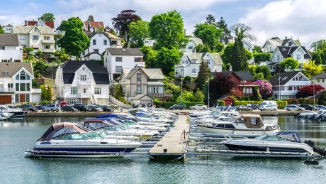 Småbåthavn full av båter, med et villastrøk i bakgrunnen.