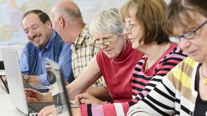 Flere eldre sitter i foran hver sin PC. 