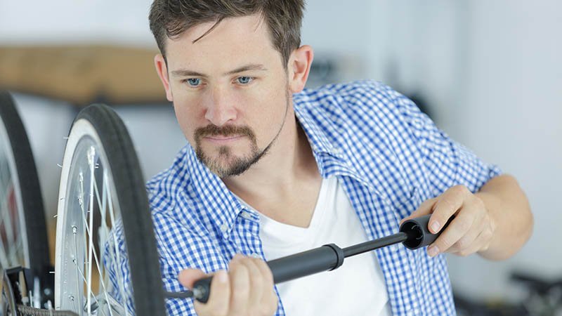 En mann fyller luft inn i dekkene på en sykkel.