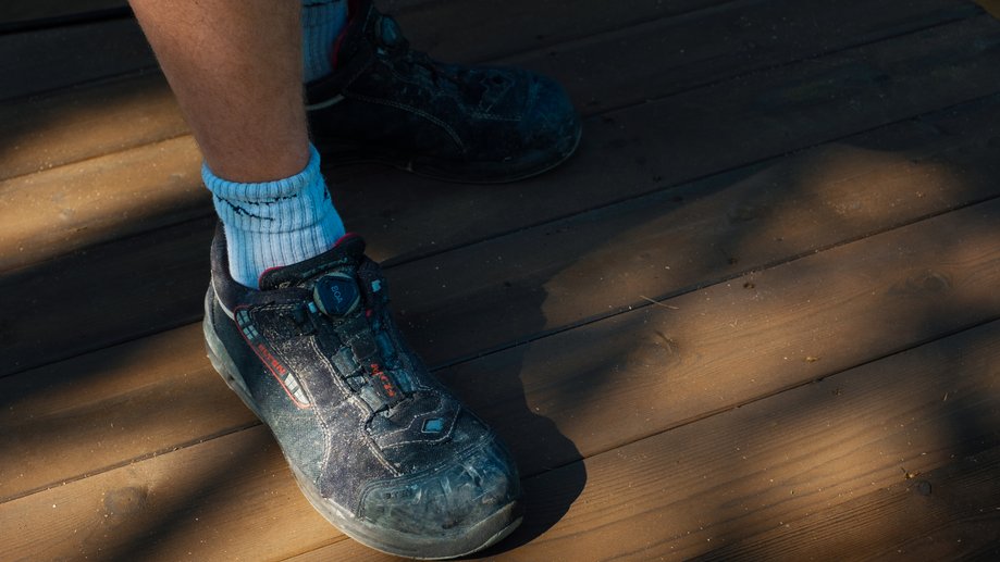 Sko og sokker på en person som står på trestokk eller treplanke.