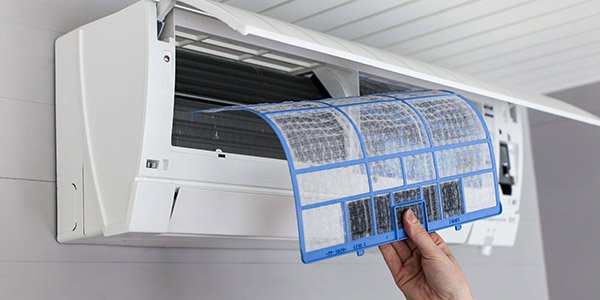 Hånd som fjerner filter fra en varmepumpe