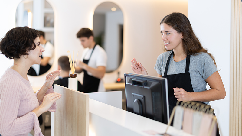 En frisør snakker med en kunde.