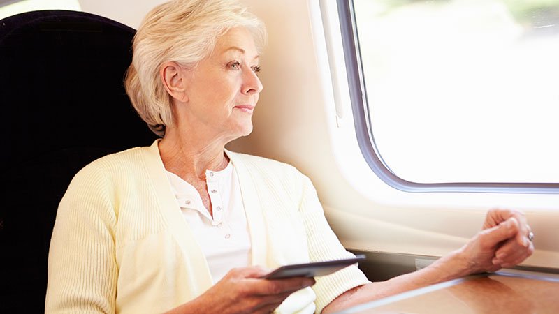 En eldre dame sitter på et tog.
