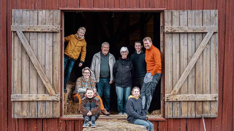 En familie står i døra til en låve.