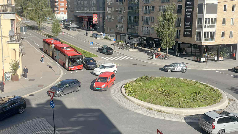 En rundkjøring med flere biler og en buss.