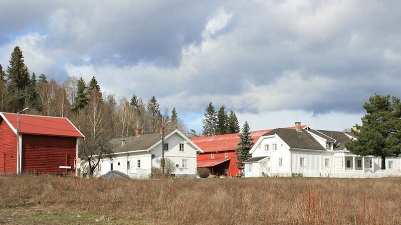 Bilde av et gårdstun med røde og hvite bygninger.