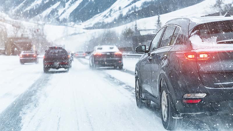 Biler kjører i nedoverbakke på vinterføre.