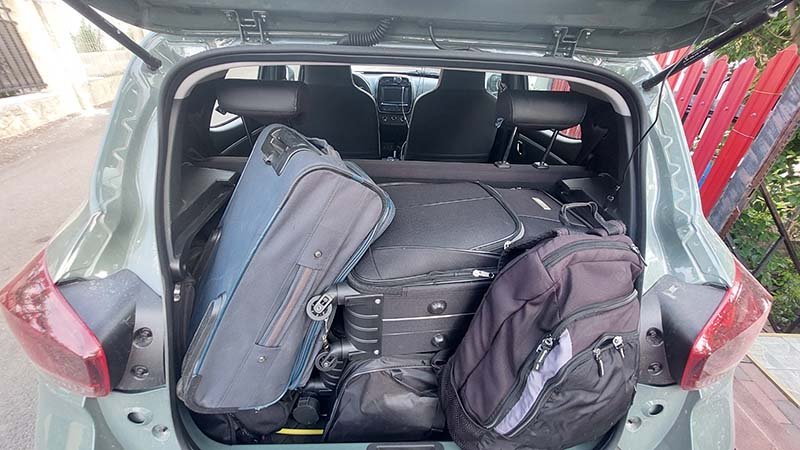 Bilbagasjerom fylt med kofferter og ryggsekk.