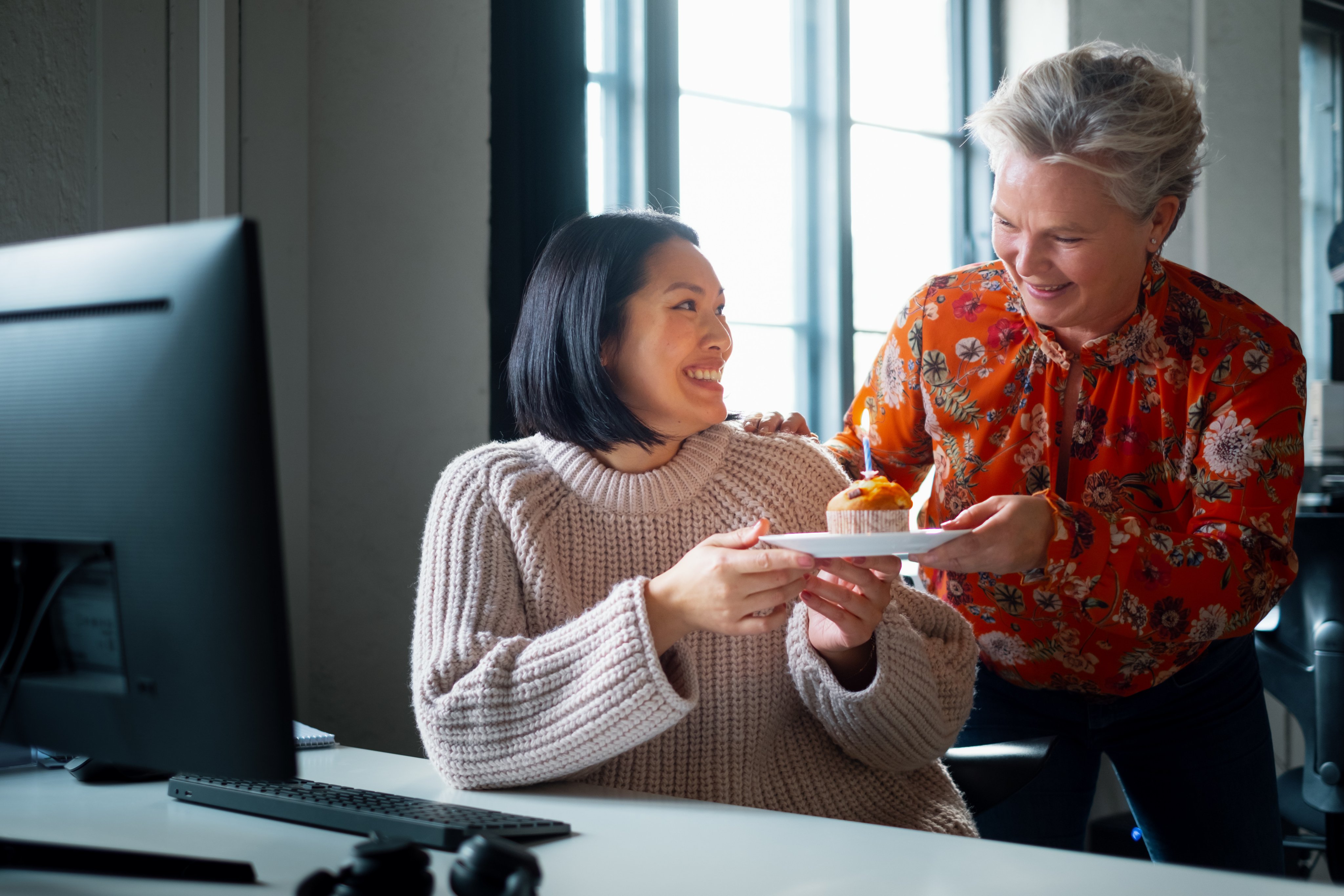 En ansatt blir overrasket med kake ved pulten.