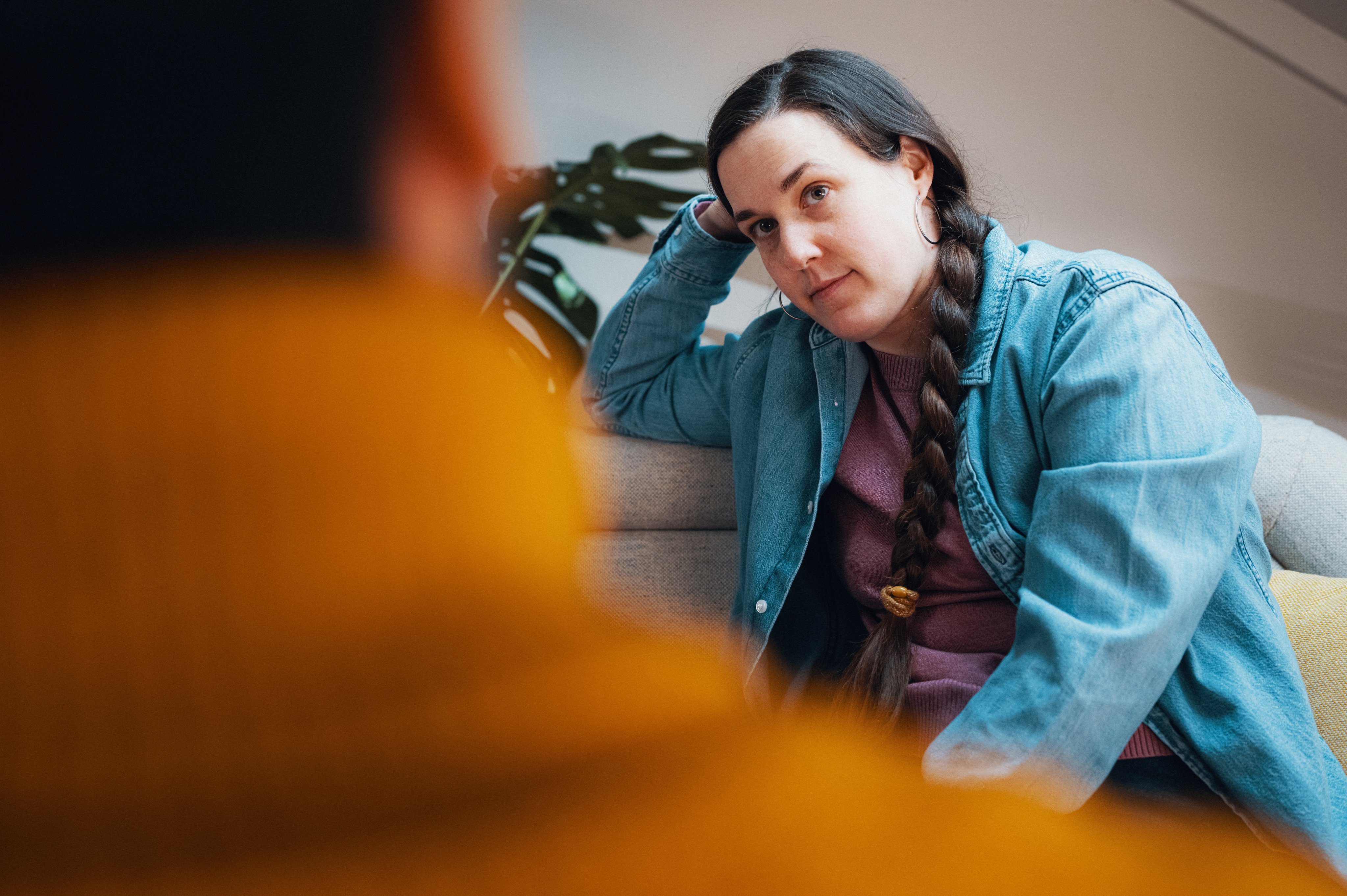 Person sitter i en sofa og lytter i en samtale, med avslappet holdning.