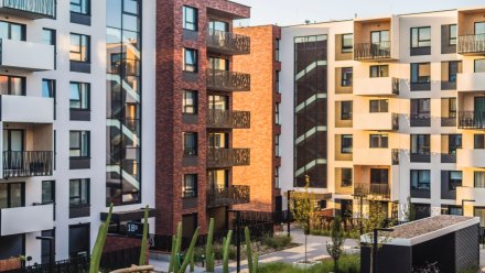 Moderne leilighetsbygg med balkonger og store vinduer i et boligområde.