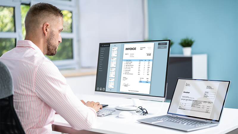 Mann som sitter foran en datamaskin og jobber med regnskap