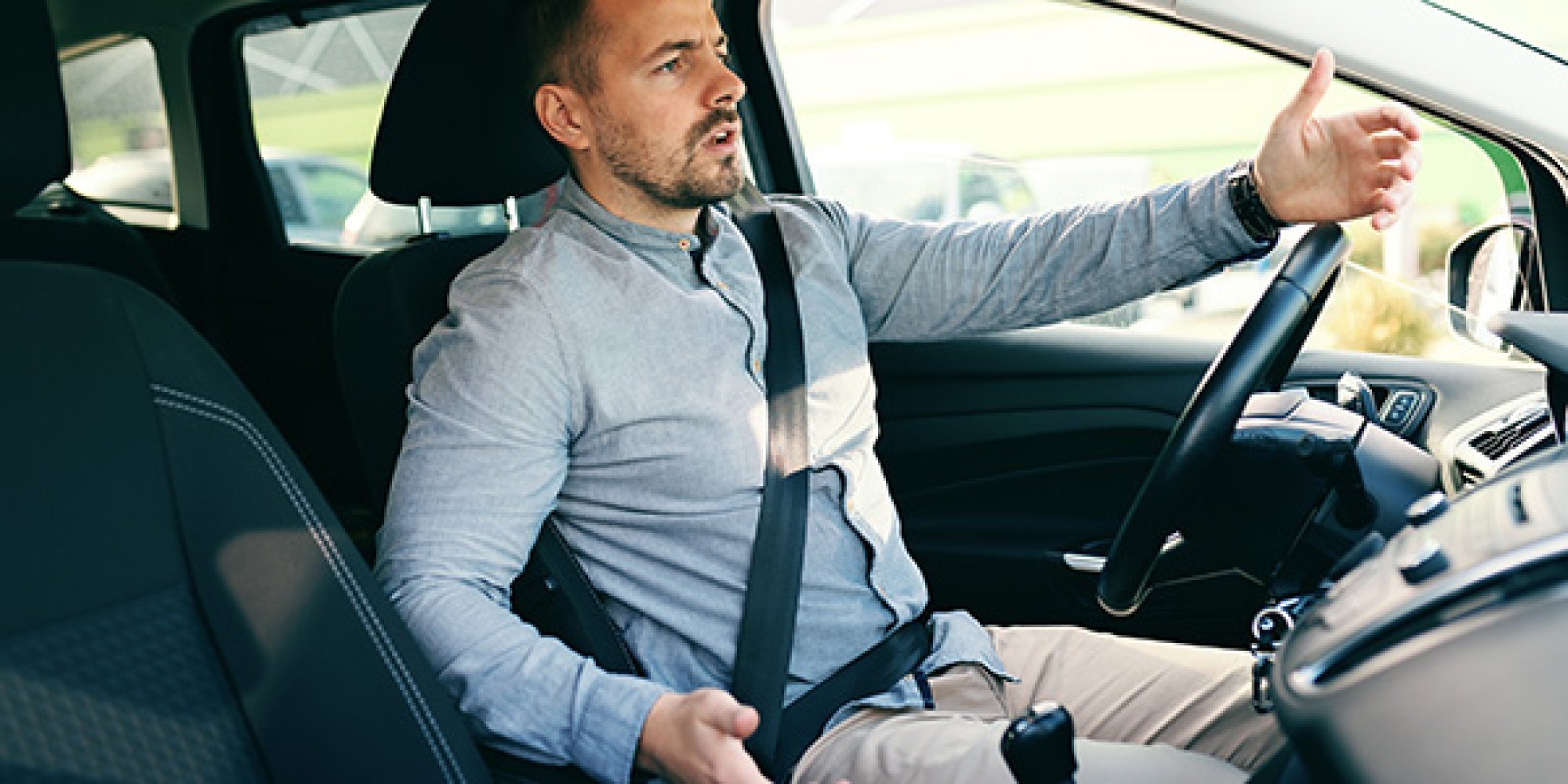 En mann sitter i en bil og ser oppgitt ut.