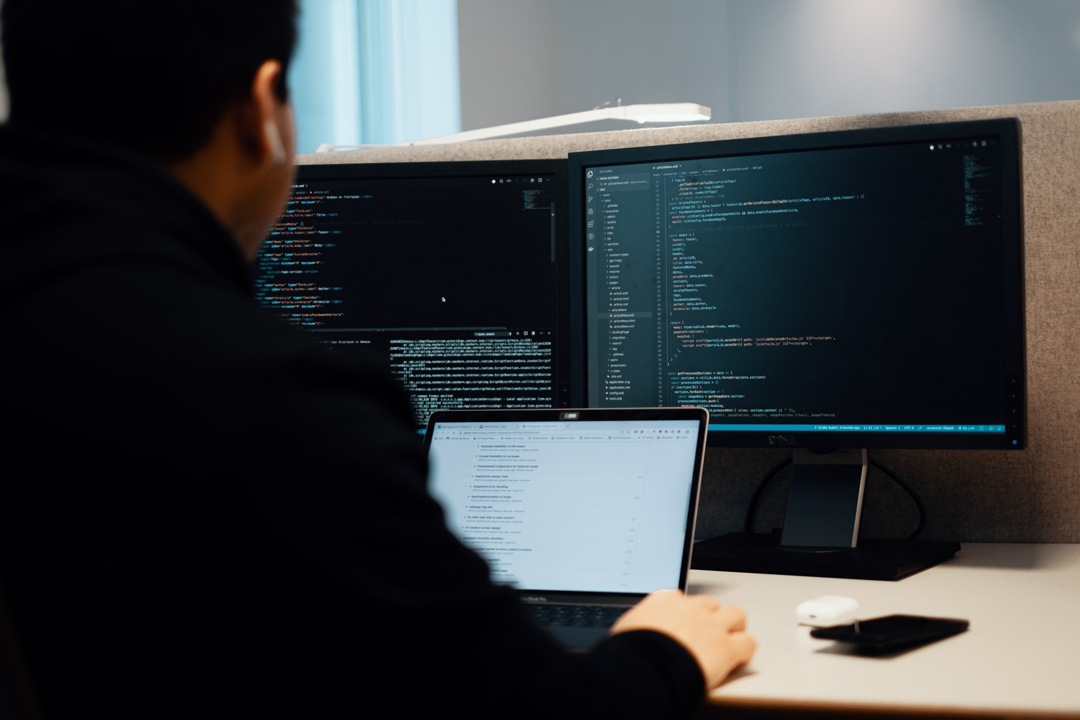 En mann sitter foran tre pc-skjermer