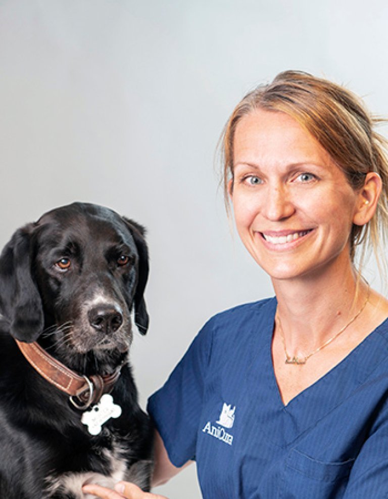 Veterinæren Sasja Rygg ved siden av en hund.