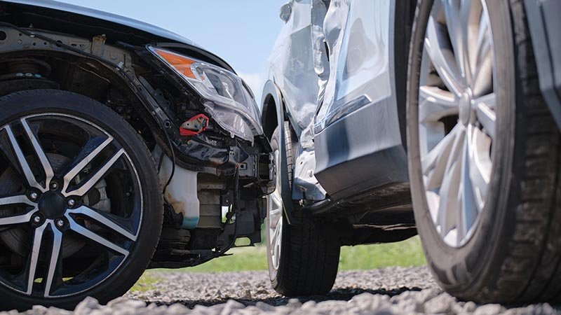 Nærbilde av en svart og en grå bil som har kraæsjet. Den grå bilen har en stor bulk i siden.