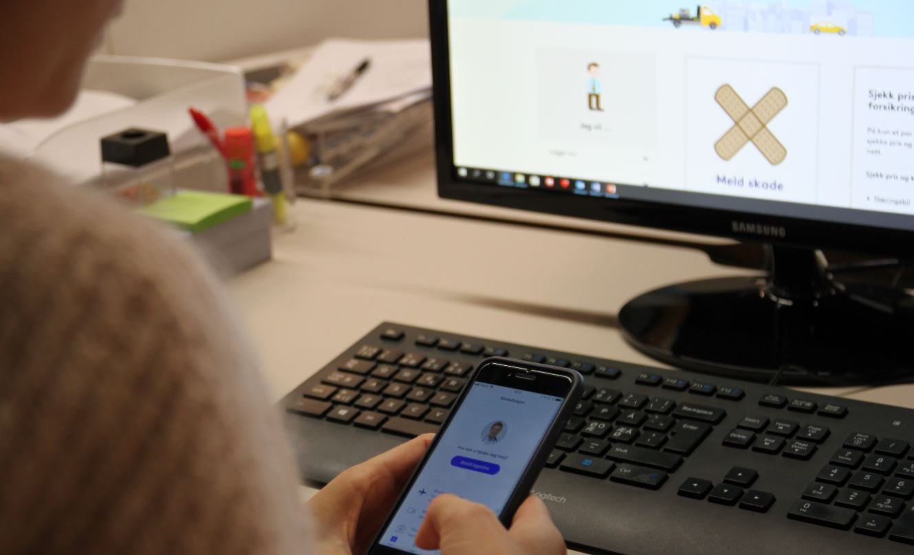 En ansatt som melder inn et behandlingsbehov på mobilen sin ved pulten.