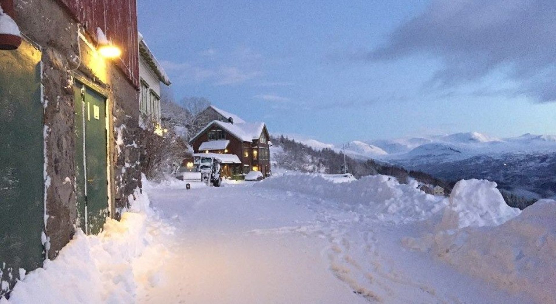 Masse snø rundt gårdsbyggninger på fjellet.