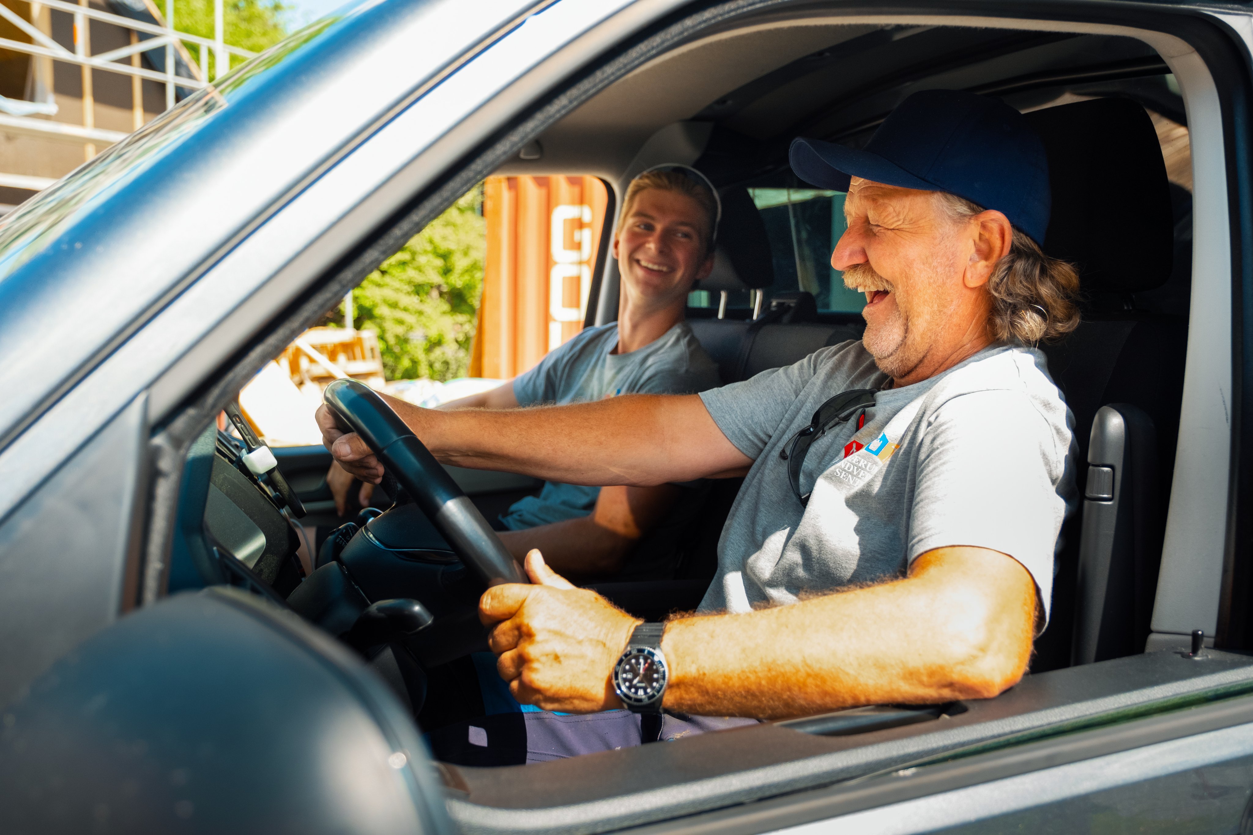 En smilende mann foran arbeidsbilen sin