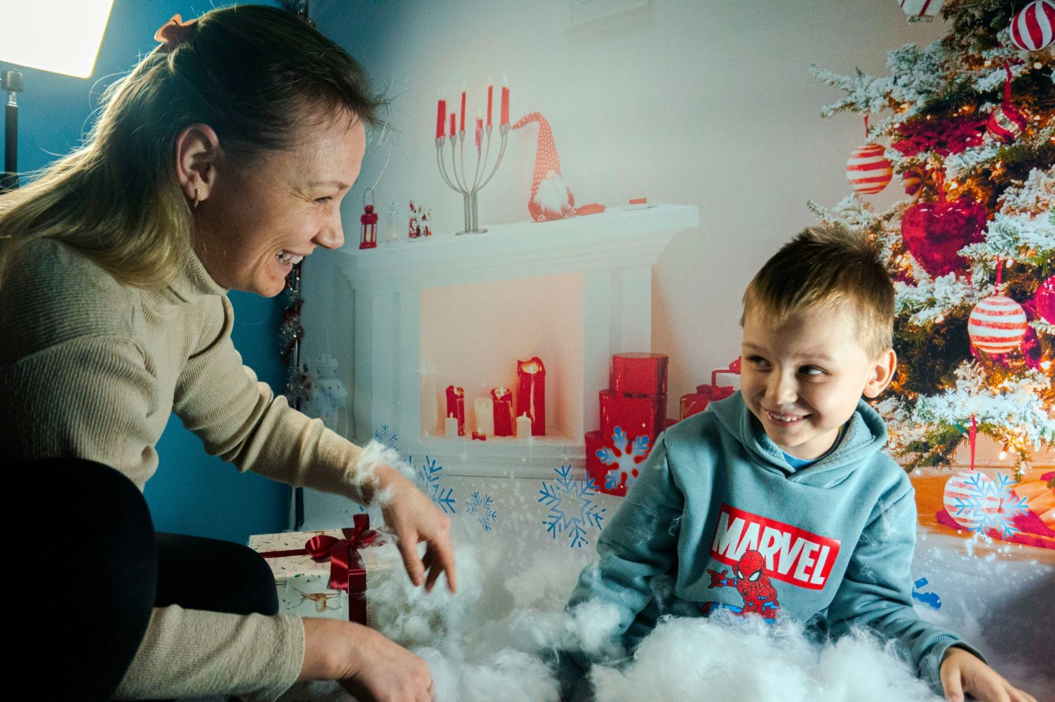 Mor og sønn sitter foran en juledekorert vegg.