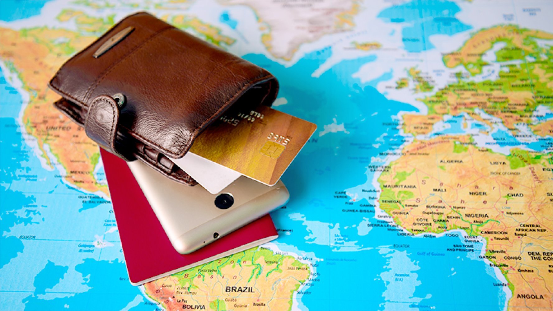 Pass, lommebok og mobiltelefon ligger på et verdenskart.
