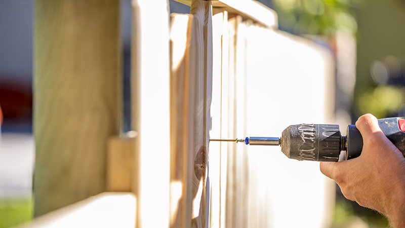 En hånd som driller i et gjerde 