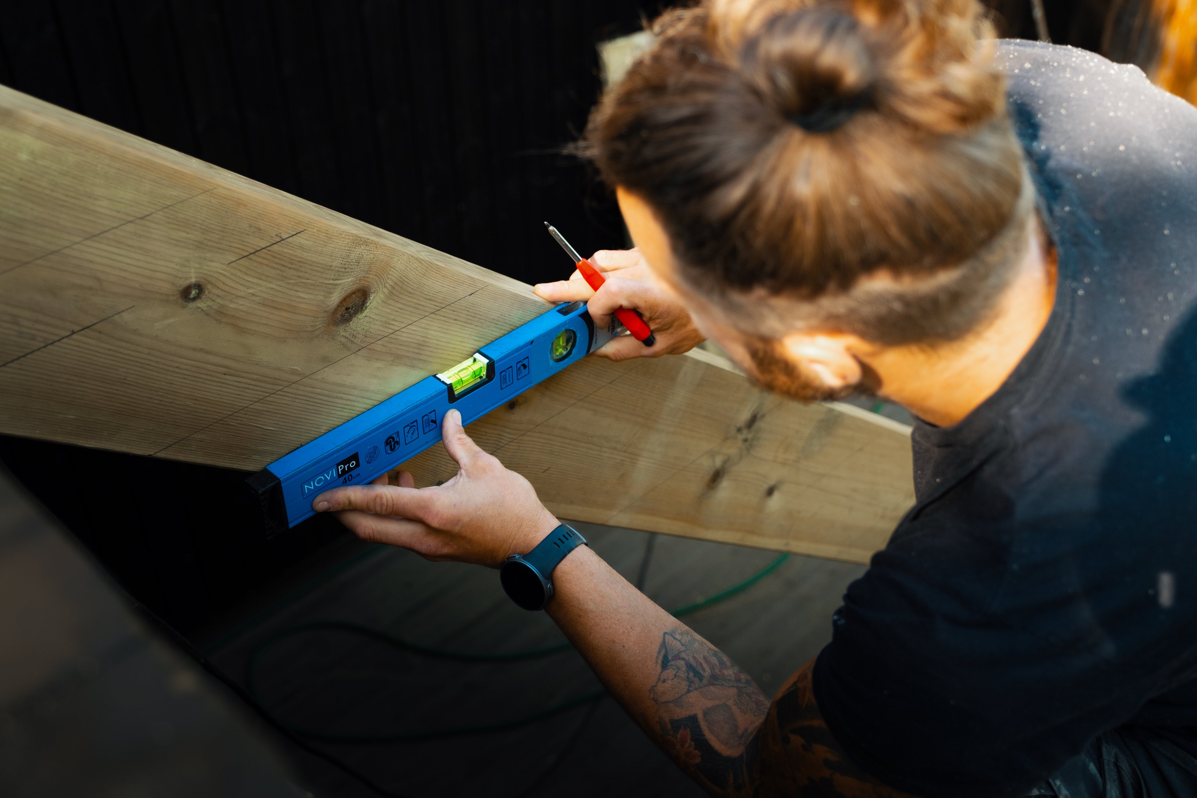 Håndverker måler en trapp i tre som han holder på å bygge.