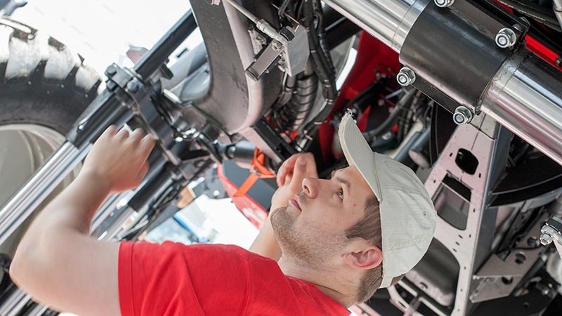 En mekaniker står under en traktor.