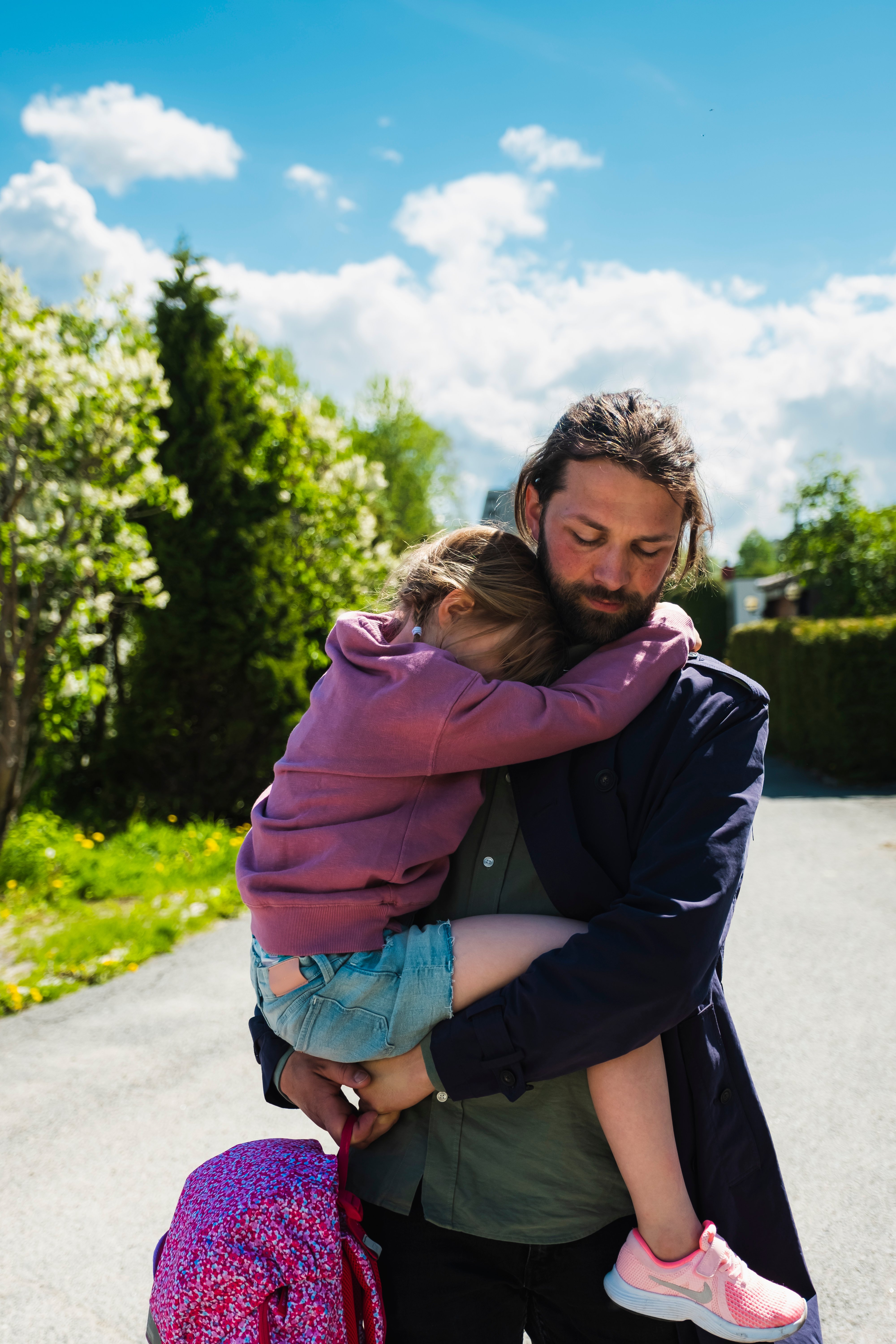 En far bærer barnet sitt langs en vei.