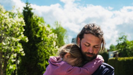 En far bærer barnet sitt langs en vei.