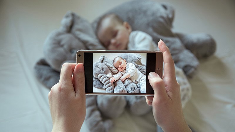 En person tar bilde av en baby med mobilen sin.