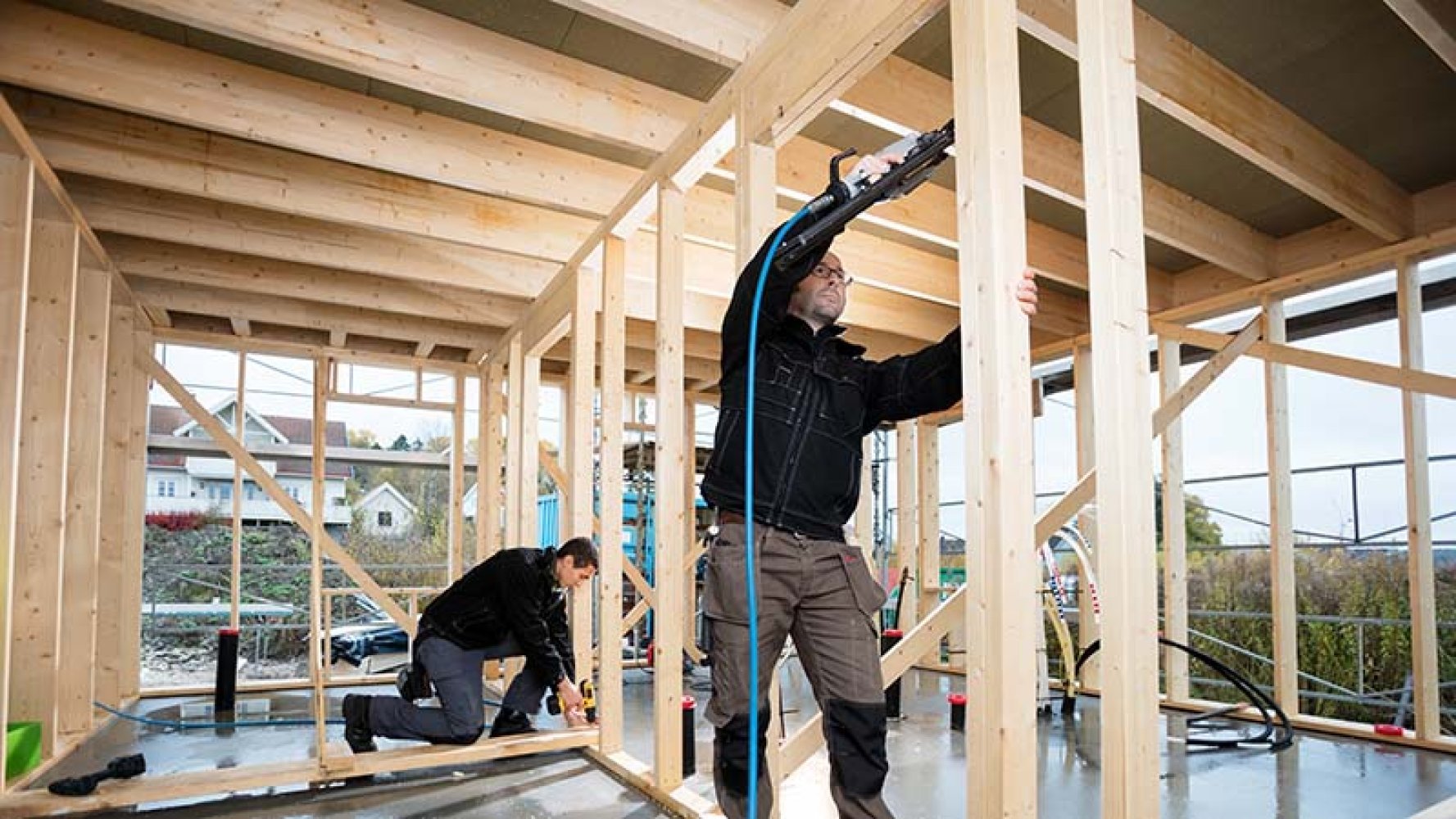 To snekkere setter opp reisverk i et nybygg.