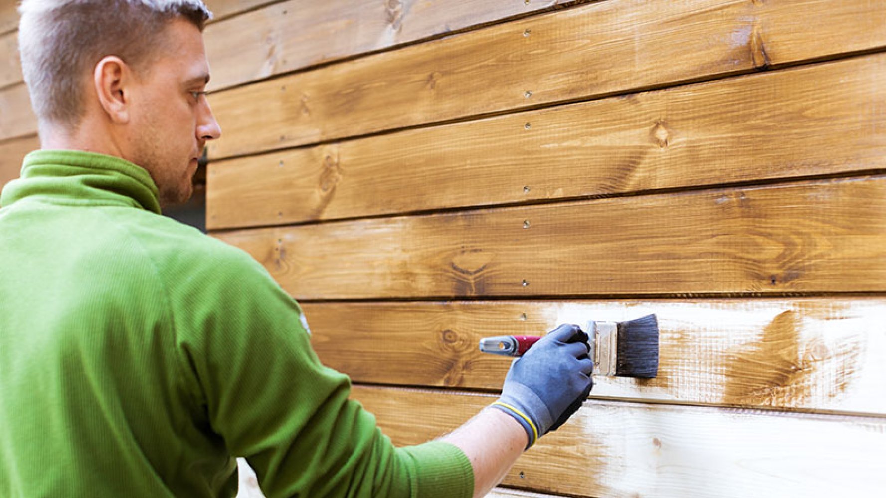 Mann maler husvegg utendørs