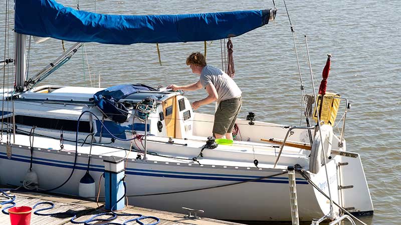 Person på seilbåt som ligger til en brygge