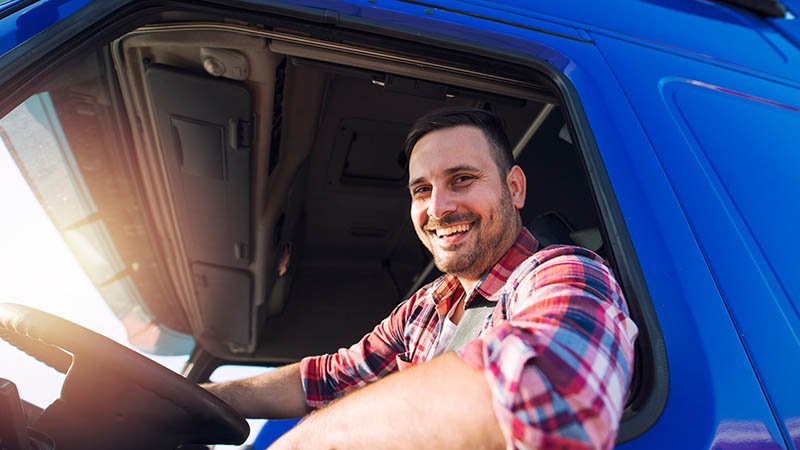 En fornøyd mann bak rattet i det som ser ut som en trailer/lastebil.