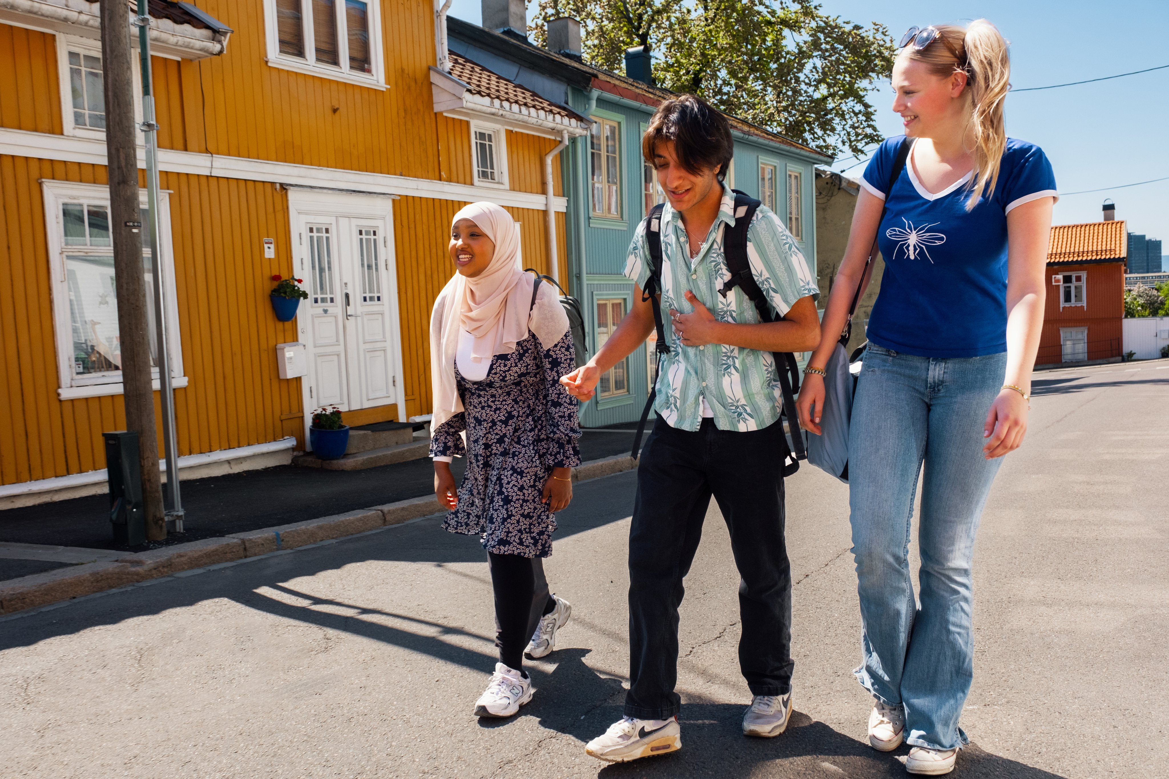 Tre unge personer går langs en vei.