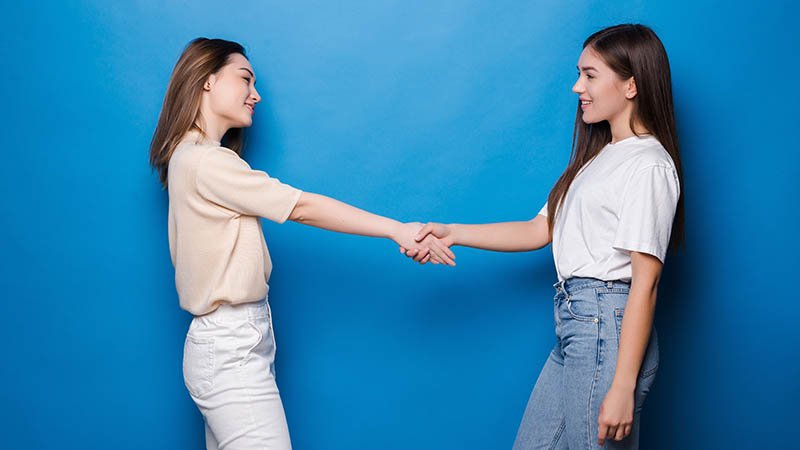 To unge kvinner håndhilser.