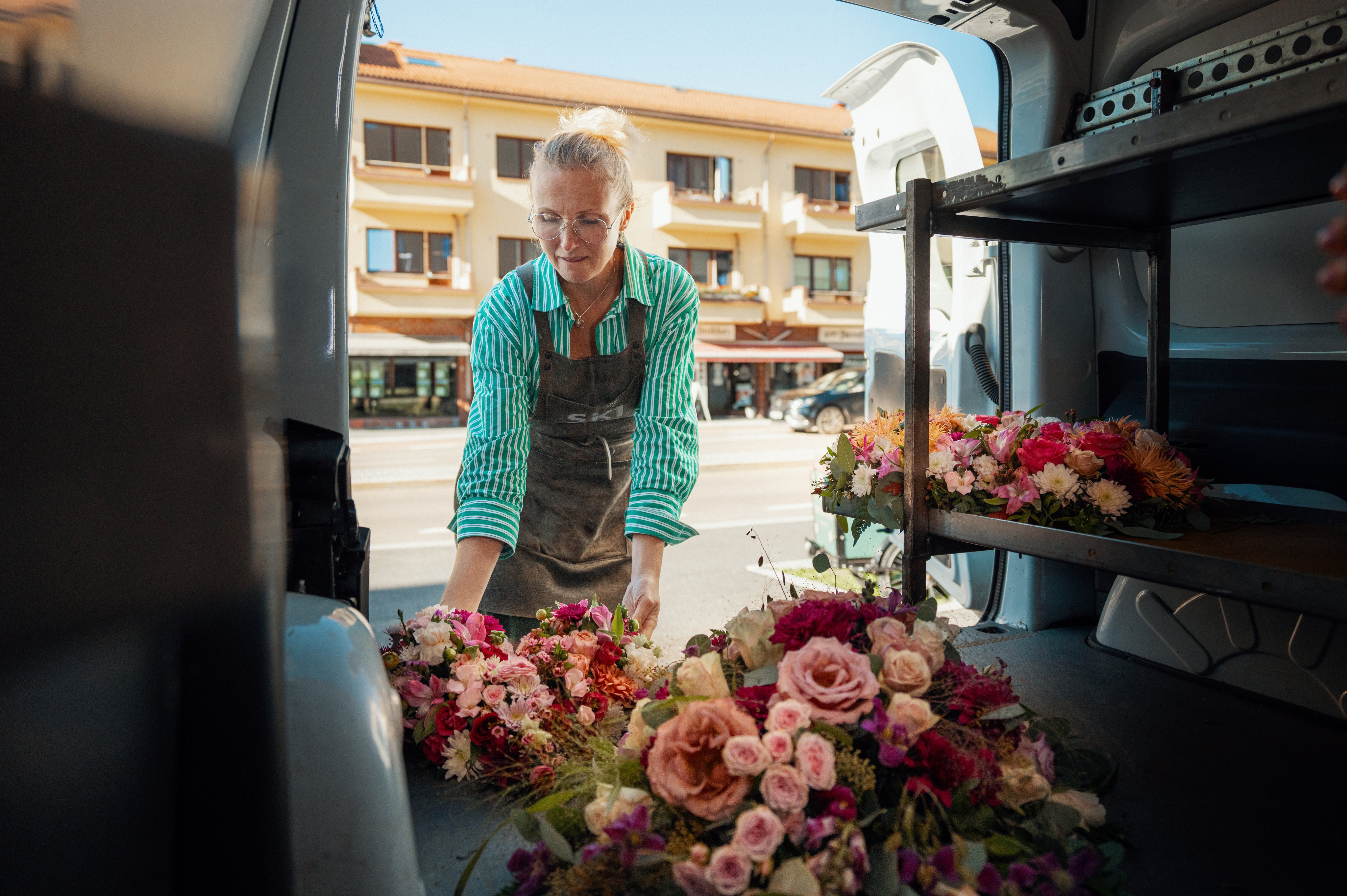 Kvinne setter inn blomster i en varebil