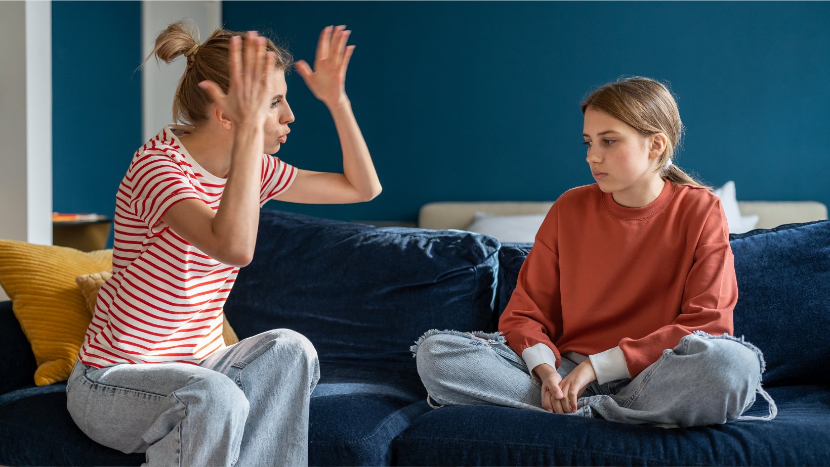 En mor og en datter sitter på en sofa. Moren kjefter på datteren.